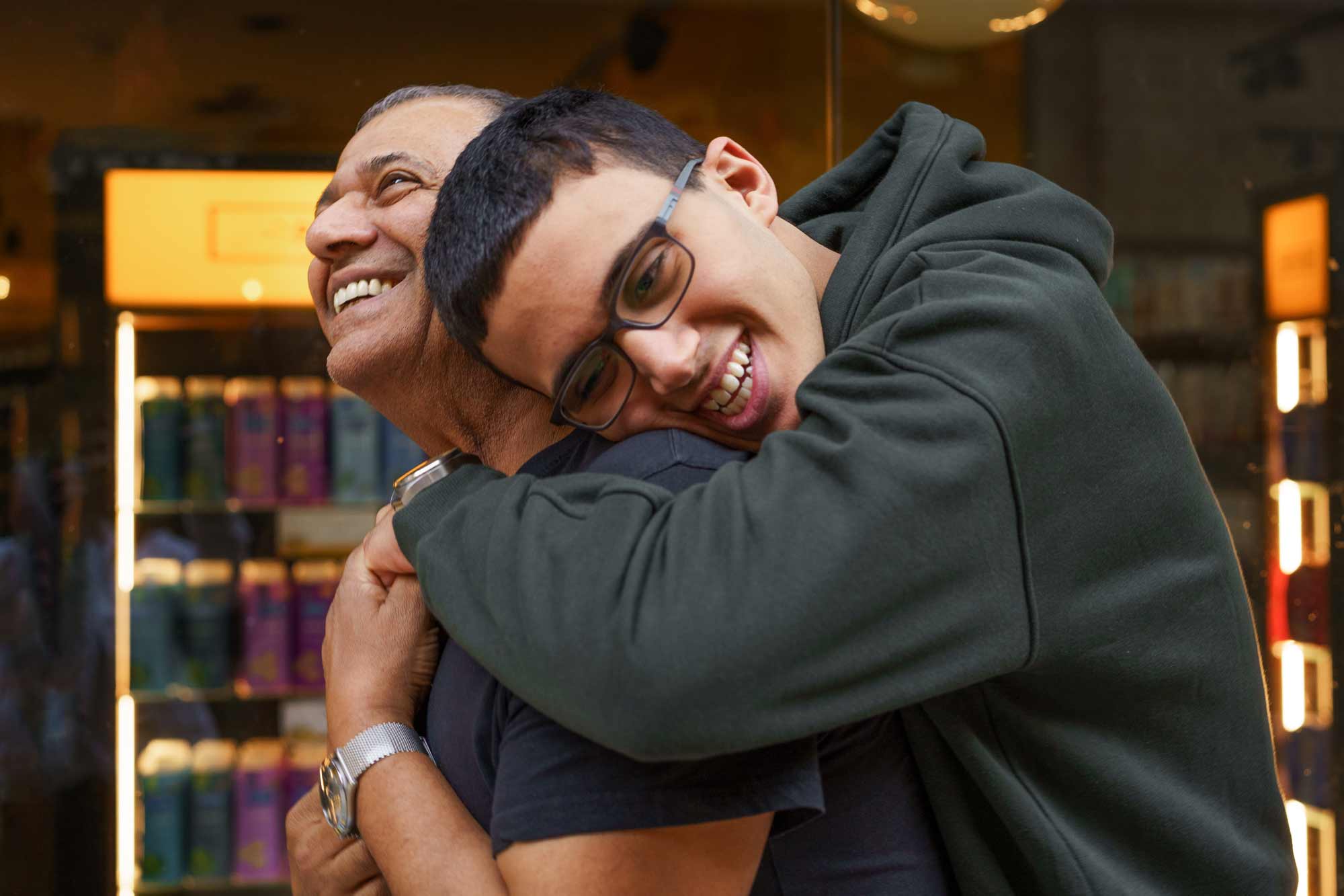 special needs teen boy leans over to hug his father